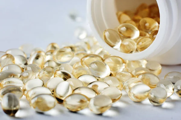 Yellow capsules of vitamin D on a gray surface.