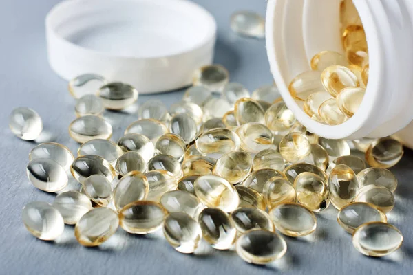 Yellow capsules of vitamin D on a gray surface.
