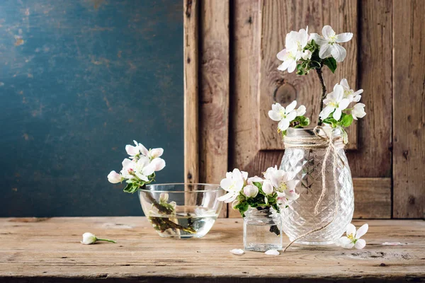 Ahşap bir arka planda cam bir kasede elma çiçeği.