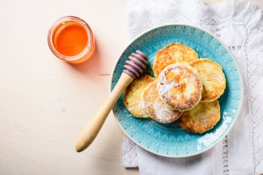 Açık ahşap arka planda ballı süzme peynir krepleri..