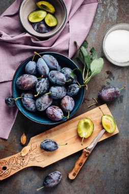 Bir kasede taze mavi erikler ve doğranmış erikler..