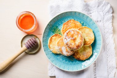 Açık ahşap arka planda ballı süzme peynir krepleri..