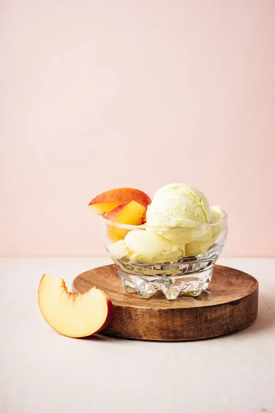 Scoop of peach ice cream in a glass.