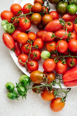 Various fresh ripe tomatoes on a white tray.