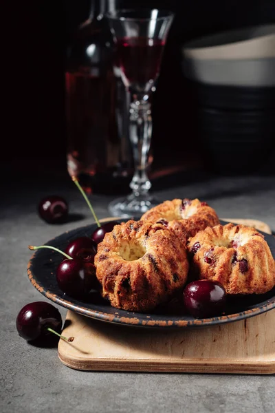 Mini bundt cakes with cherries on a dark background.