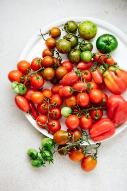 Various fresh ripe tomatoes on a white tray.