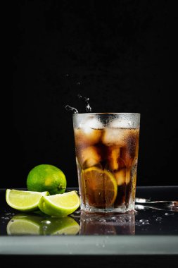 Siyah arka planda limonlu Küba libre kokteyli..