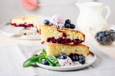 Two pieces of blueberry sponge cake with berry ice cream.