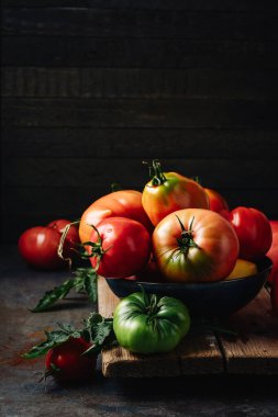 Koyu arkaplanda taze taze koparılmış kırmızı organik domatesler..