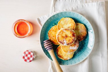 Mavi tabakta bal ile servis edilen süzme peynirli krep..