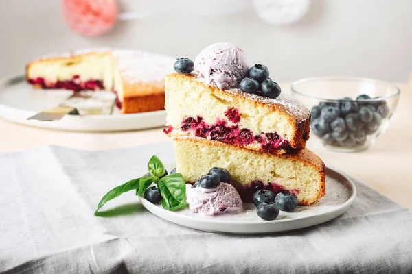 Two pieces of blueberry sponge cake with berry ice cream.