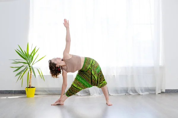 Fiatal nő gyakorló jóga, álló Utthita Trikonasana gyakorlat, kiterjesztett háromszög póz — Stock Fotó