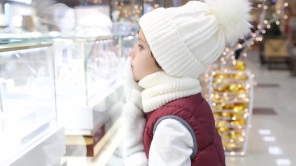 Rapazes de chapéu Santas olham para a loja pela janela do mercado. luzes brilhantes no fundo. — Vídeo de Stock