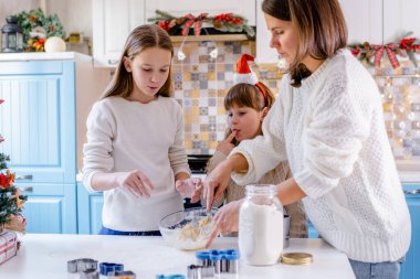 Anne ve çocuklar bayram yemeği hazırlıyorlar. Kızlar Noel için kurabiye pişirir.