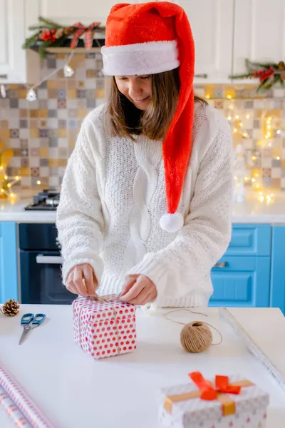 Woman in Santa hat packing Christmas gifts — Stock Photo, Image