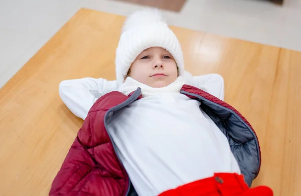 Lindo chico en un sombrero blanco esponjoso en un centro comercial contra el fondo de luces brillantes —  Fotos de Stock