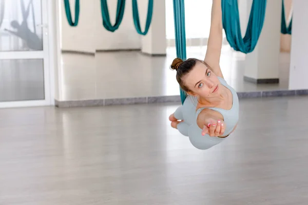 Bella giovane donna sorridente, guardando la fotocamera e utilizzando amaca per lo yoga — Foto Stock