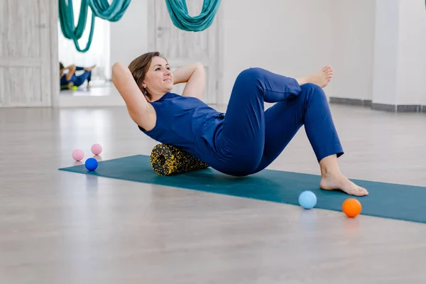 Brunnet Woman lie on yogi mat use Myofascial release massage roll on back