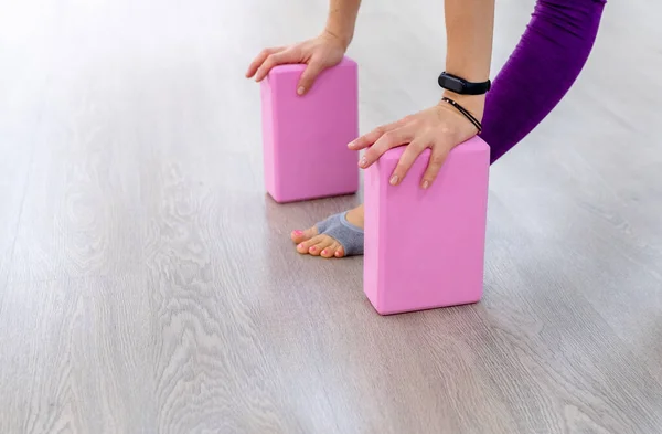 Close-up uma mulher inclina as palmas das mãos em blocos de ioga rosa. conceito acessórios e equipamentos de ioga — Fotografia de Stock