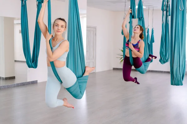 Kelompok dari dua wanita muda yogi melakukan yoga anti gravitasi terbang menggunakan hammock biru bersama-sama — Stok Foto