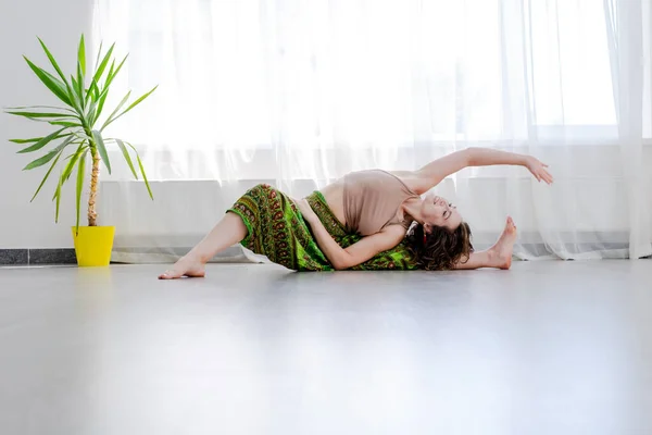 Egy nő jógázik a padlón. A hatha jóga fogalma — Stock Fotó