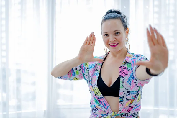 Esmer kadın 30-35 yaşlarında gülümsüyor ve Zumba dansını seviyor. Tüm dünyada aktif dans kavramı