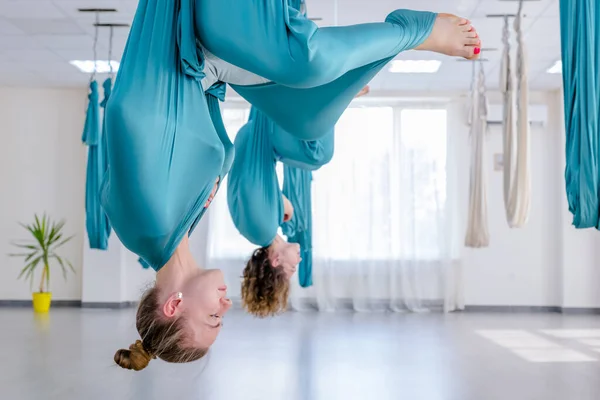Skupina dvou mladých jogínů dělá létat jógu pomocí bílého houpací sítě spolu Stock Snímky