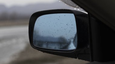 Arabanın yan aynasına yağmur damlaları düşer.