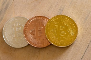 Tahta bir masanın üzerinde altın, gümüş ve bakır bitcoin