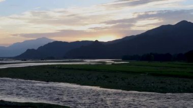 The landscape of river swat and mountain with orange glow in clouds at sunset in Swat valley, Khyber Pakhtunkhwa, Pakistan