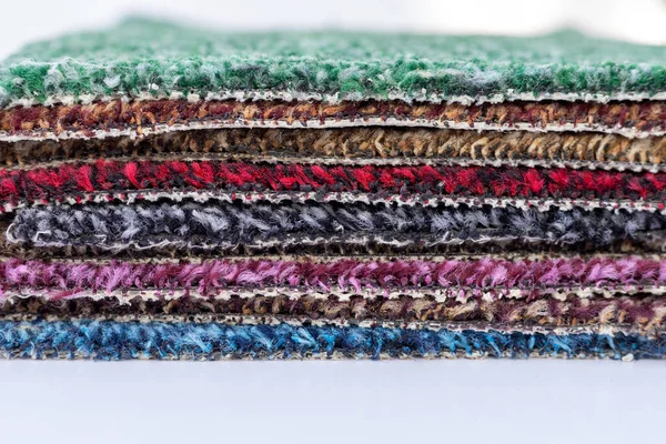 A set of colorful carpet sample stack over each other in the store with selective focus and on isolated white background