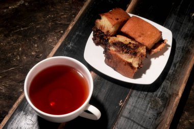 Bir fincan çay ve eski bir tahta üzerinde bir tabak martabak.