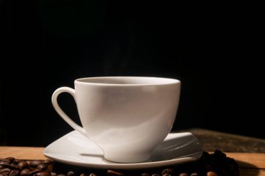 Kahve çekirdekleri arasında seramik kahve fincanı