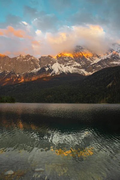 Gün batımı. Zugspitze Dağı ve Eibzee Gölü. Bavyera Alpleri. Almanya. Ormandan güzel dağ manzaraları görülebilir..