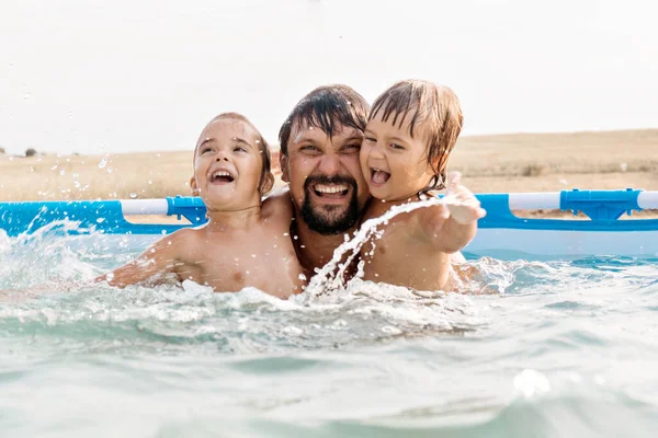 Een man met een kind die in het zwembad zwemt. Papa met dochter in het water — Stockfoto