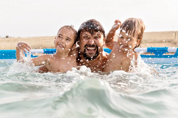 Un homme avec un enfant nageant dans la piscine. Papa avec sa fille dans l'eau Image En Vente