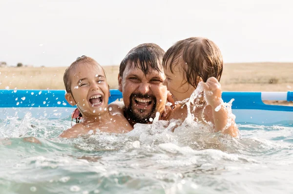 En mann med barn som svømmer i bassenget. Far med datter i vannet. stockfoto