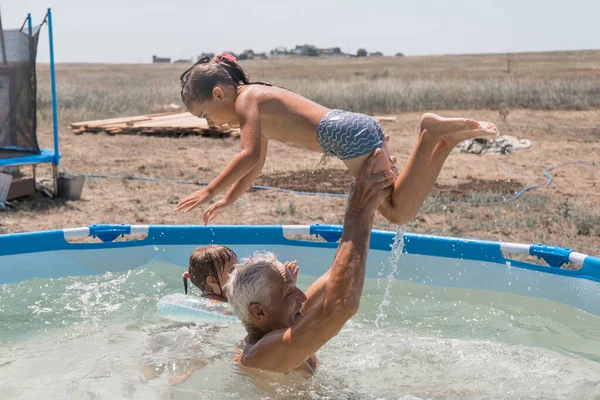 Een man met een kind die in het zwembad zwemt. Papa met dochter in het water Stockafbeelding