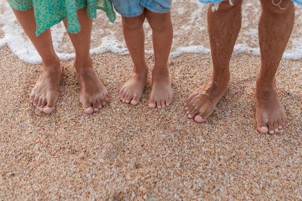 Opálené nohy v písku zblízka. na písek se valí vlna. letní dovolená u moře — Stock fotografie