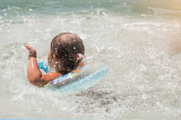 Une fille dans un cercle gonflable pour nager en vacances dans la piscine, la mer. Concept spa, cours de natation, vacances, traitements de l'eau — Photo