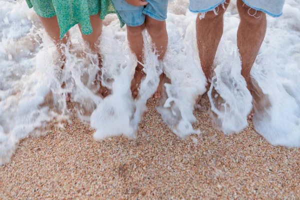 Opalone nogi w piasku z bliska. Fala toczy się na piasek. letnie wakacje nad morzem — Zdjęcie stockowe