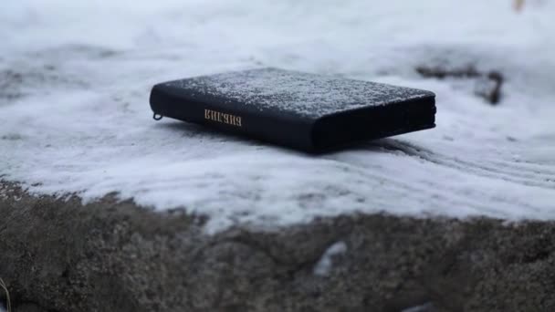 Μαύρη Αγία Γραφή γκρο πλαν. Χιόνι πέφτει στο βιβλίο. Ο Λόγος του Θεού για τα Χριστούγεννα — Αρχείο Βίντεο