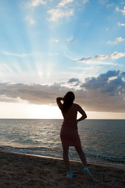 Reis naar de zee. Een meisje in een jurk en hoed loopt langs het strand. een toeristische wandeling langs de zeekust. warme tochten tijdens de vakantieperiode. kopieerruimte — Stockfoto