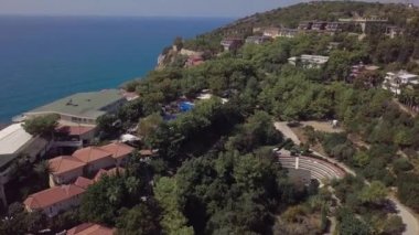 Deniz ve otel manzarası, sıcak bir yaz gününde ağaçlar yeşil bir palmiye ağacının çalısı yüzünden. tatil