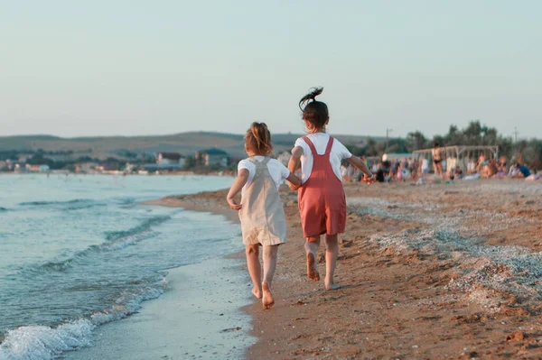 Ferie til sjøs. En familie går langs stranden. barn som holder hender – stockfoto