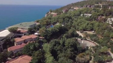 Deniz ve otel manzarası, sıcak bir yaz gününde ağaçlar yeşil bir palmiye ağacının çalısı yüzünden. tatil