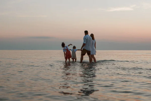 Denizde tatil. Bir aile sahil boyunca yürür. Aile el ele tutuşuyor — Stok fotoğraf