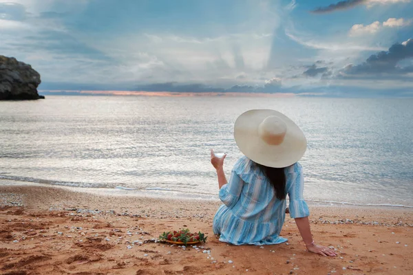 Dieta. Alimentação saudável e descanso. mulher bebe água limpa no fundo de vidro mar e come morangos. Uma mulher na praia gosta da vida — Fotografia de Stock