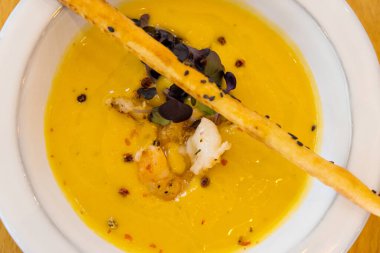 Patates ve fesleğenli kabak çorbası. Sarı masadaki parlak yemek.