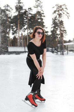 Buz üstünde artistik patinajcı. Kız kayıyor. Açık gökyüzünün altındaki buz. Kışın makyaj yok, kırmızı yanak.